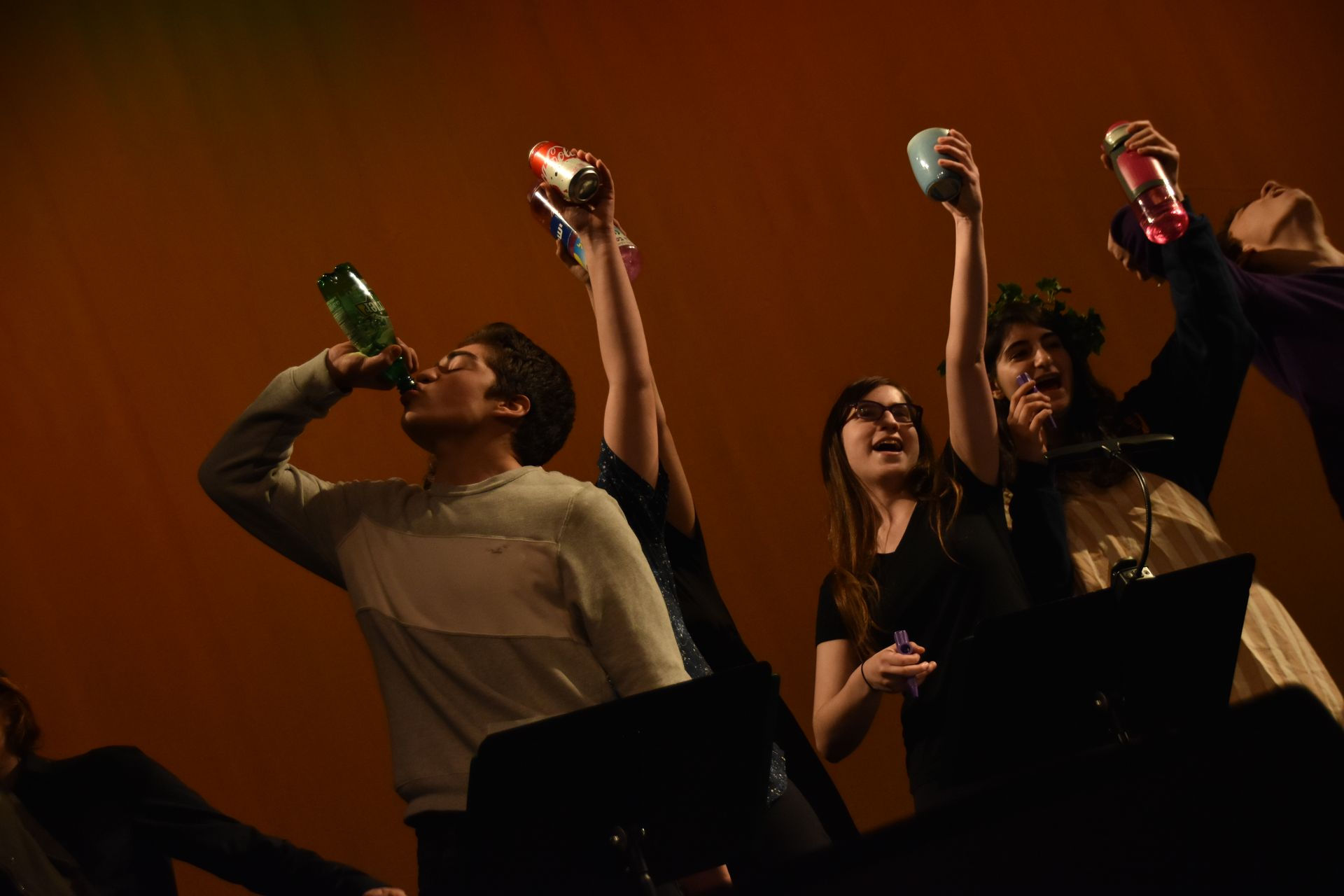 A group of people holding bottles and cans up in a toast.