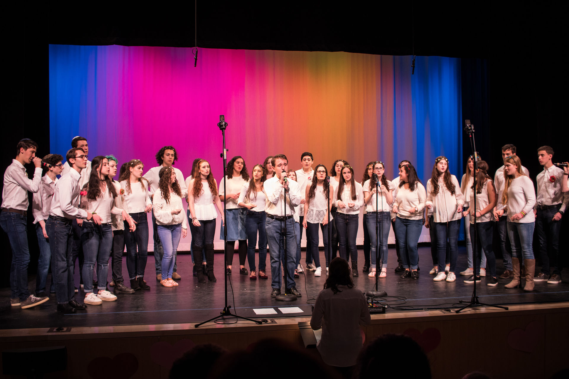 A group of singers on stage in front of a multicolored background.